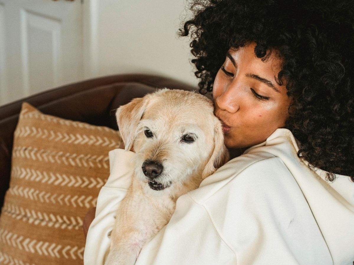 young-girl-hugging-her-golden-retriever-dog-by-a-large-tree-1200x900-1 woman happily kissing her small dog at home
