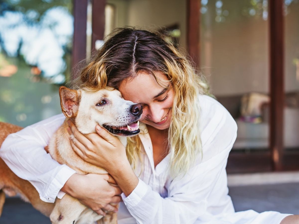 A person is hugging their dog while sitting on a porch A person is hugging their dog while sitting on a porch